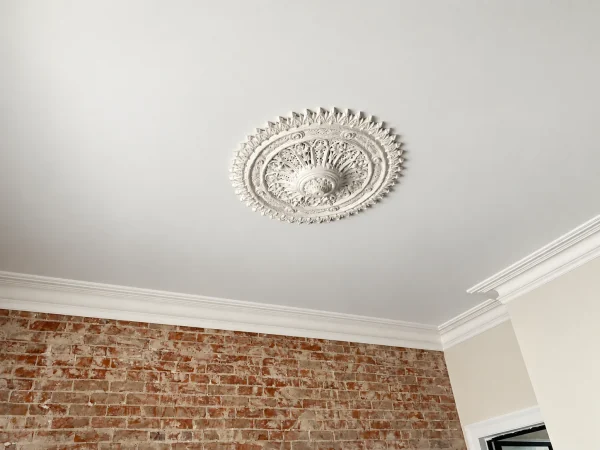 Finish visualisation of an ornate round ceiling rose above an exposed brick wall