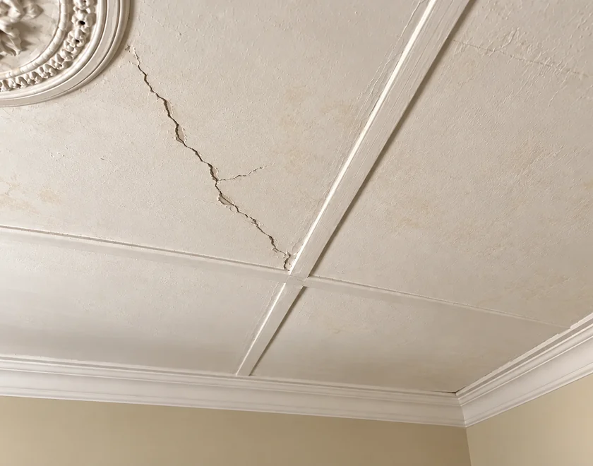 AI visualisation of an ageing plaster ceiling with a prominent natural crack and chipped paint edges.