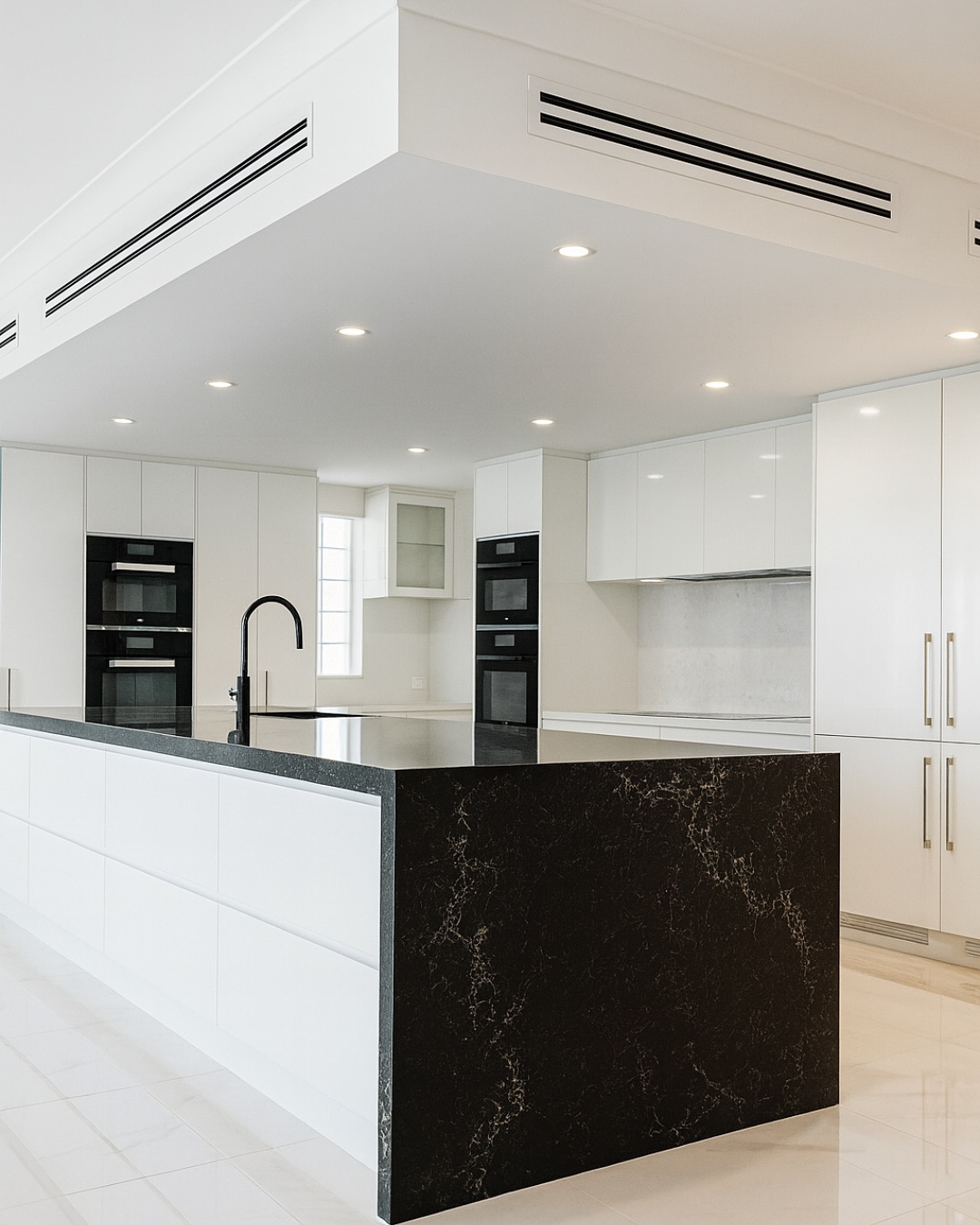 North Haven kitchen island with deep black stone waterfall end and integrated wall ovens