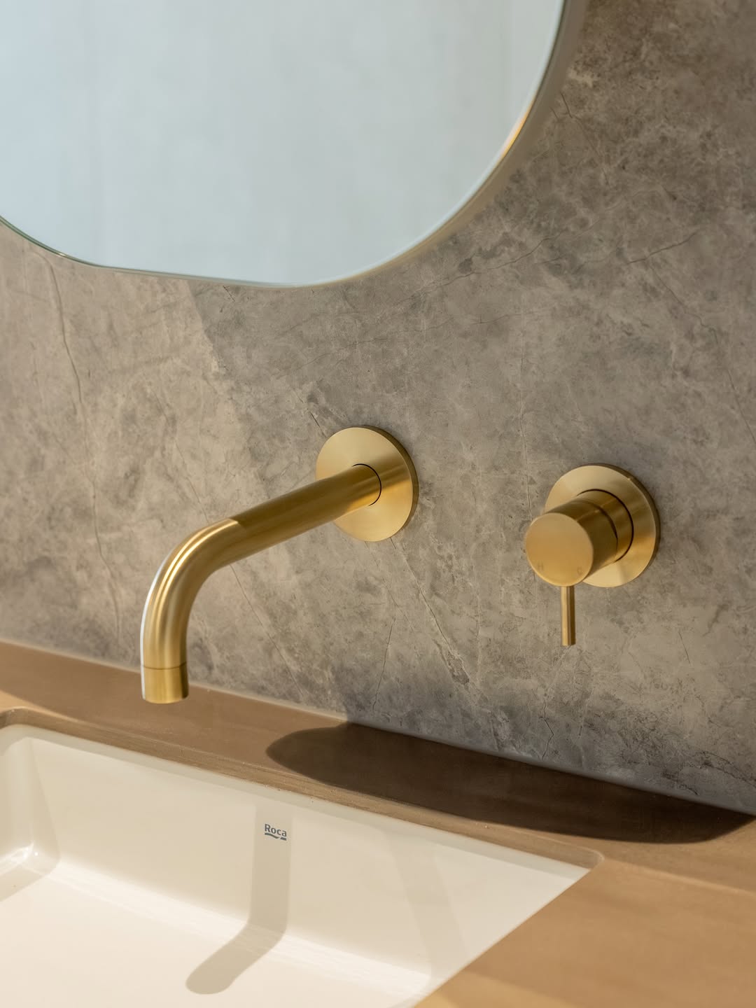 Brushed brass basin mixer and stone-look wall tile detail