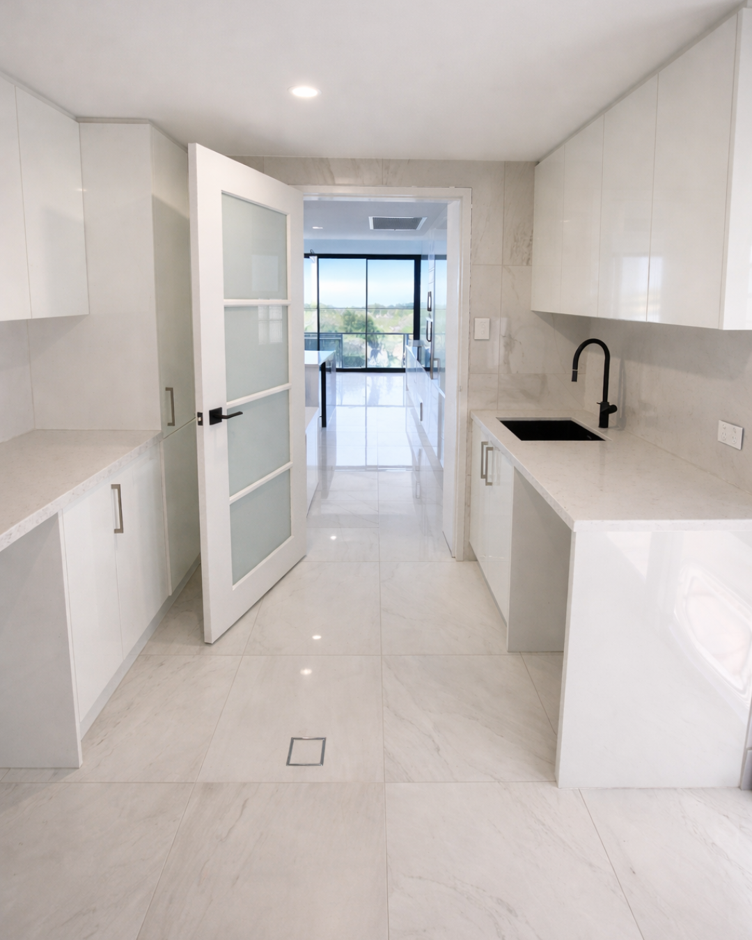 Bright Northhaven laundry with long bench runs, white cabinetry and kitchen connection
